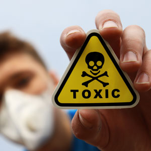 Man in mask holding toxic sticker, symbolizing toxic tort litigation. - Robichaux Law Firm, LLC.